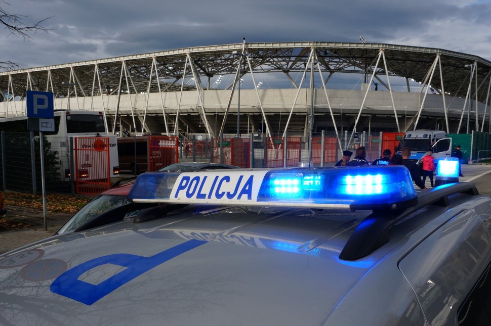 Policyjny radiowóz, w tle korona stadionu miejskiego.