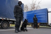 Dwóch policjantów stoi z psami służbowymi.