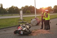 Dwaj policjanci stoją obok przewróconego motocykla.